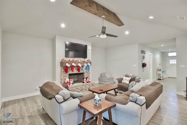 living room with light wood-type flooring, a fireplace, ceiling fan, and vaulted ceiling