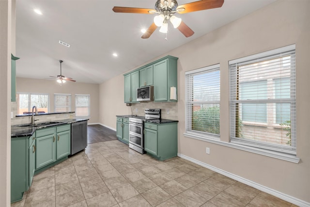 kitchen with appliances with stainless steel finishes, lofted ceiling, sink, backsplash, and green cabinets