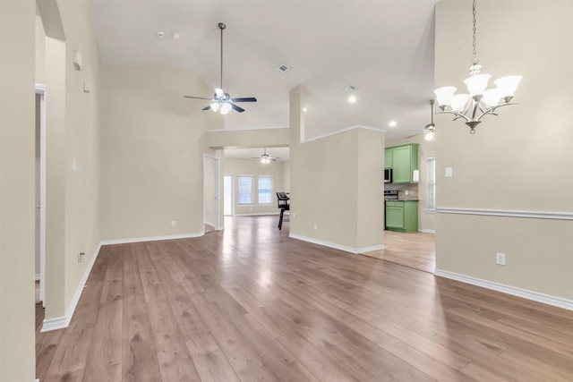 unfurnished living room featuring ceiling fan with notable chandelier, vaulted ceiling, and light wood-type flooring