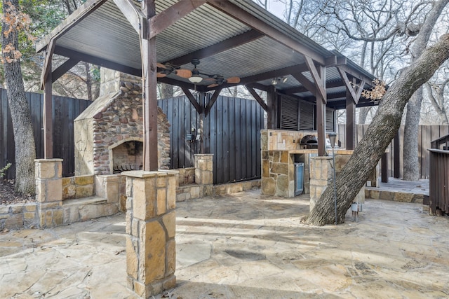 view of patio with ceiling fan and an outdoor stone fireplace