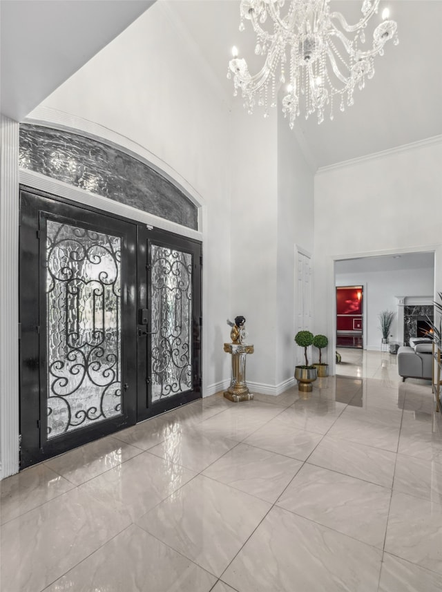 entrance foyer with french doors, crown molding, a high ceiling, and a notable chandelier