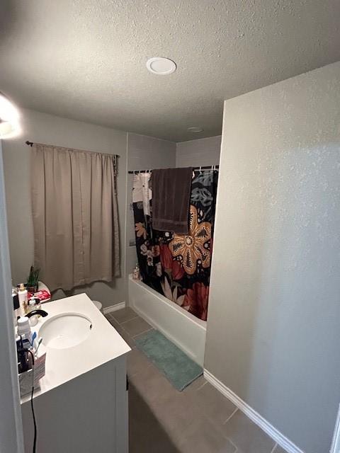 bathroom with tile patterned floors, vanity, shower / bathtub combination with curtain, and a textured ceiling