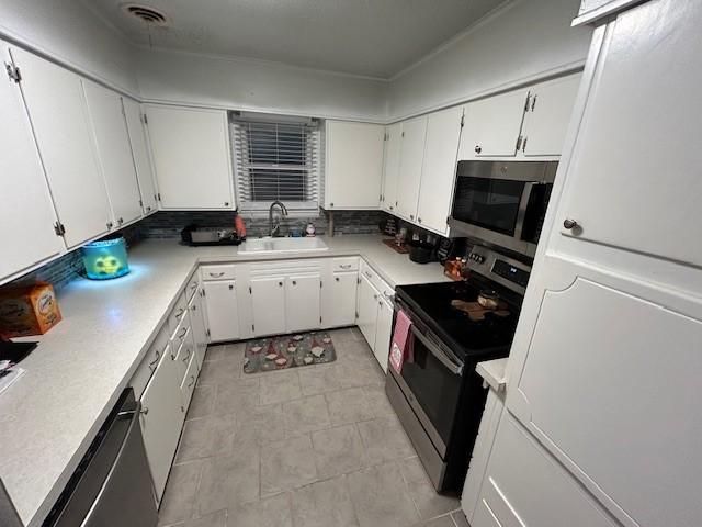 kitchen featuring appliances with stainless steel finishes, backsplash, white cabinetry, and sink