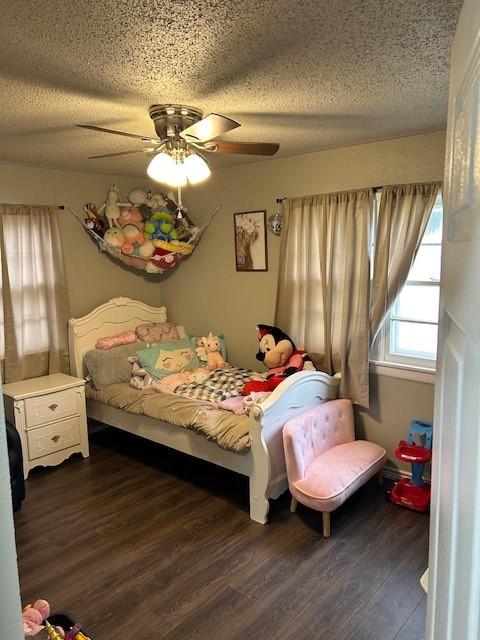 bedroom with ceiling fan, dark hardwood / wood-style flooring, and a textured ceiling