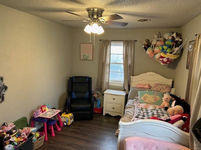 bedroom with a textured ceiling, dark hardwood / wood-style floors, and ceiling fan