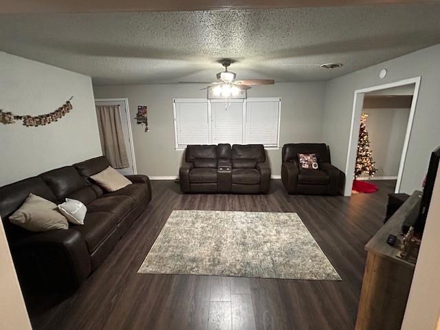 living room featuring ceiling fan, dark hardwood / wood-style flooring, and a textured ceiling