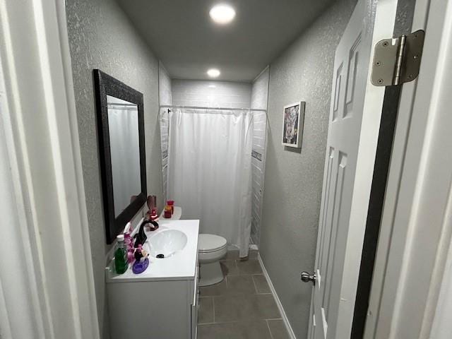 bathroom featuring tile patterned flooring, vanity, toilet, and walk in shower