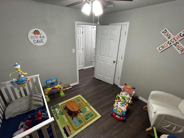 game room with ceiling fan, dark hardwood / wood-style flooring, and a textured ceiling