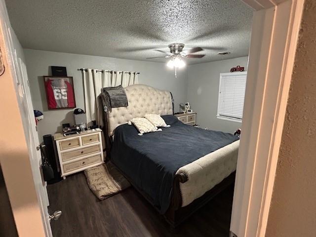 bedroom featuring ceiling fan, dark hardwood / wood-style flooring, and a textured ceiling