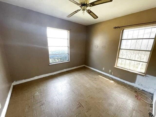 unfurnished room featuring a wealth of natural light, baseboards, and ceiling fan