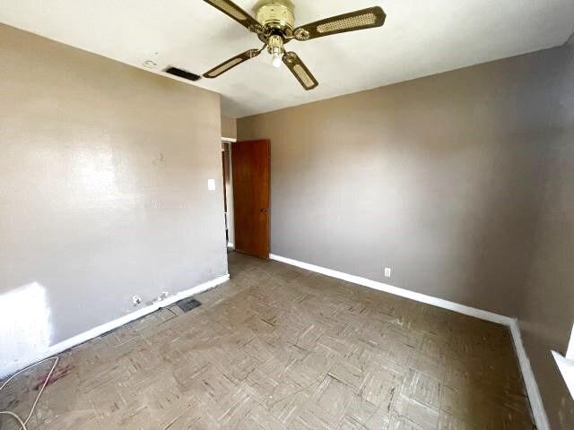 unfurnished room featuring visible vents, a ceiling fan, and baseboards