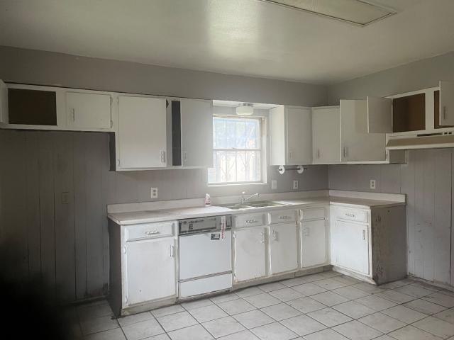 kitchen with white cabinetry, sink, wooden walls, and white dishwasher