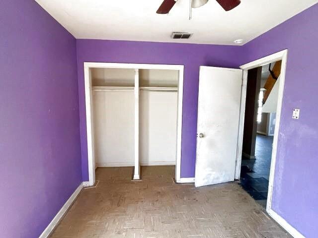 unfurnished bedroom with a closet, visible vents, ceiling fan, and baseboards