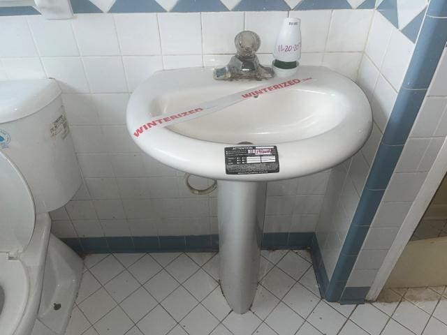 bathroom featuring toilet, tile walls, and tile patterned flooring