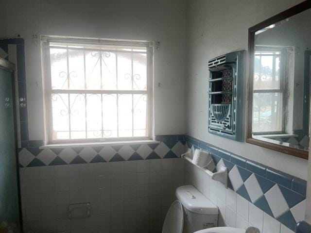 bathroom featuring toilet and tile walls