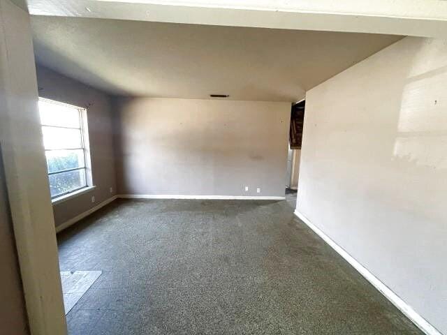 spare room featuring baseboards and dark colored carpet