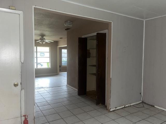 tiled empty room featuring ornamental molding and ceiling fan