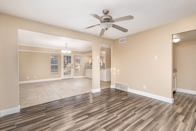 unfurnished living room with ceiling fan with notable chandelier and wood-type flooring