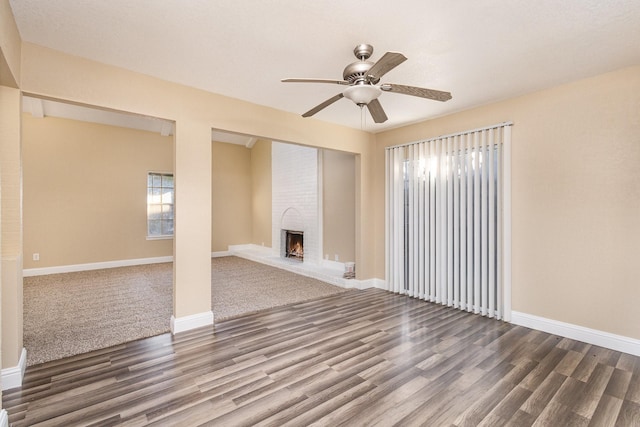 unfurnished living room featuring dark hardwood / wood-style flooring, a brick fireplace, and ceiling fan