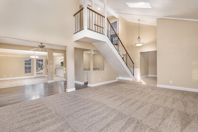 unfurnished living room with ceiling fan, light hardwood / wood-style floors, high vaulted ceiling, and a skylight