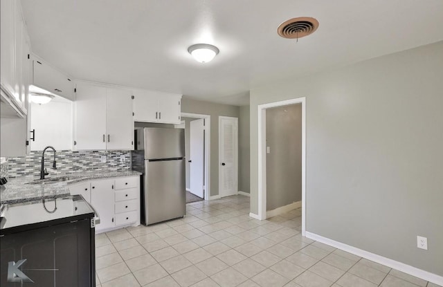 kitchen featuring sink, tasteful backsplash, stainless steel refrigerator, light stone countertops, and white cabinets