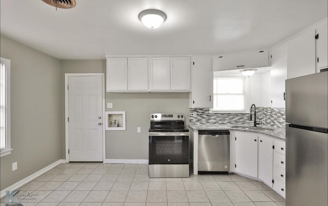 kitchen with sink, light tile patterned floors, stainless steel appliances, tasteful backsplash, and white cabinets