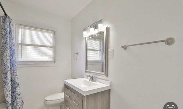 bathroom featuring vanity, walk in shower, and toilet