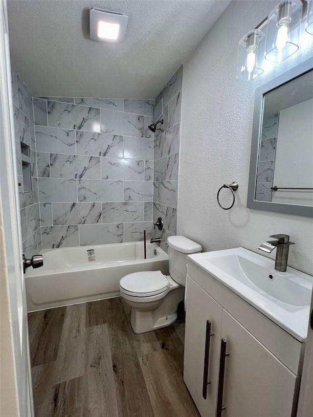 full bathroom with vanity, wood-type flooring, a textured ceiling, and tiled shower / bath