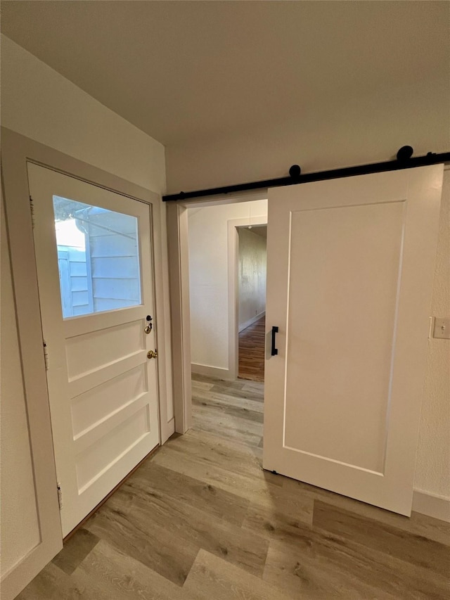 entryway featuring a barn door and light hardwood / wood-style flooring