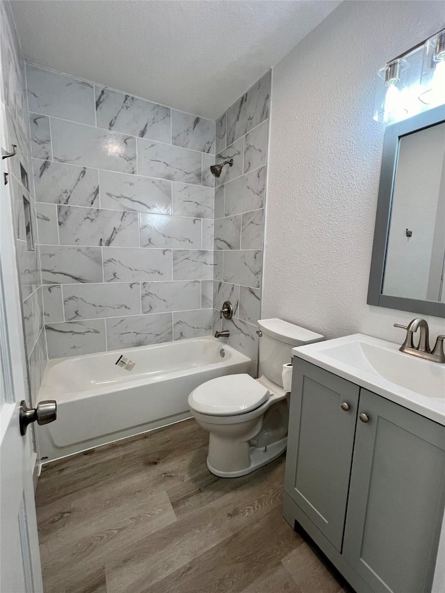 full bathroom featuring hardwood / wood-style flooring, vanity, toilet, and tiled shower / bath