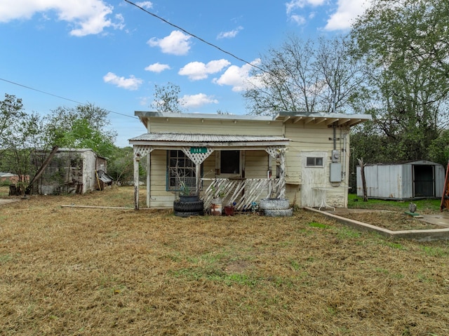 back of house with a storage unit, covered porch, and a yard