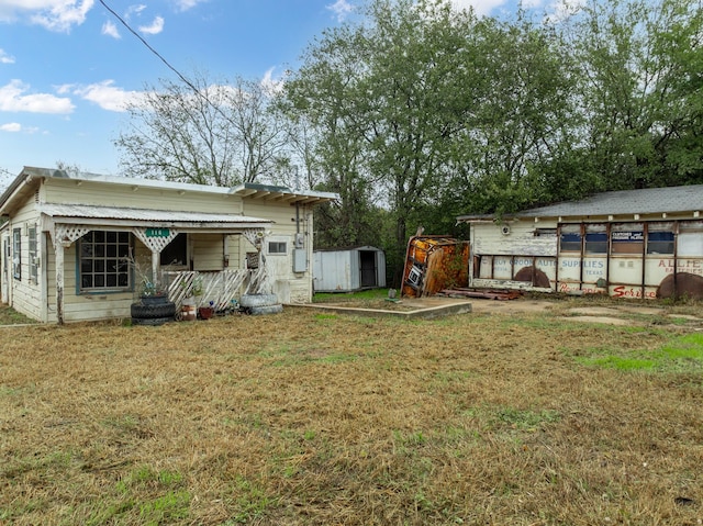 back of house with a storage shed and a yard