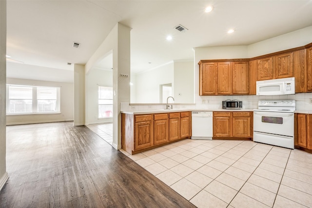 kitchen featuring white appliances, sink, light hardwood / wood-style flooring, decorative backsplash, and ornamental molding