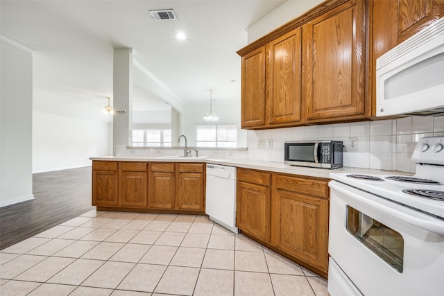 kitchen featuring kitchen peninsula, light wood-type flooring, ceiling fan with notable chandelier, white appliances, and sink