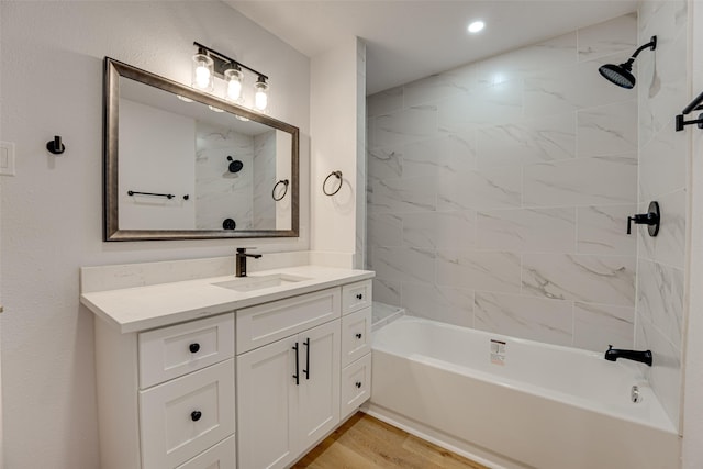 bathroom with hardwood / wood-style floors, vanity, and tiled shower / bath combo