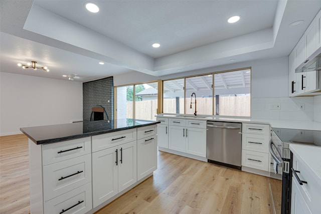 kitchen with decorative backsplash, appliances with stainless steel finishes, sink, light hardwood / wood-style flooring, and white cabinets