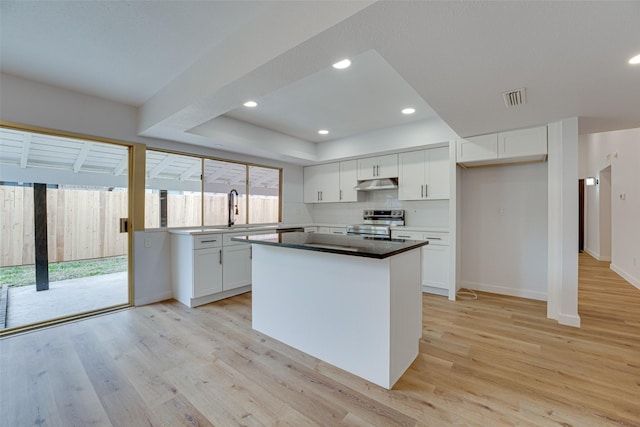 kitchen featuring sink, electric stove, white cabinets, a center island, and light hardwood / wood-style floors