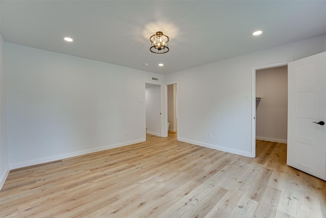 empty room featuring an inviting chandelier and light wood-type flooring