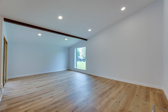 spare room with vaulted ceiling with beams and light hardwood / wood-style flooring