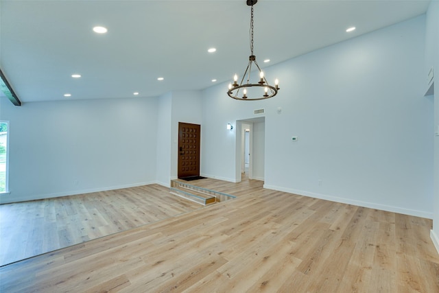 unfurnished room featuring light wood-type flooring, high vaulted ceiling, and a notable chandelier