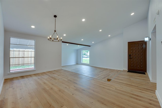 unfurnished room with light hardwood / wood-style floors, lofted ceiling, and a chandelier