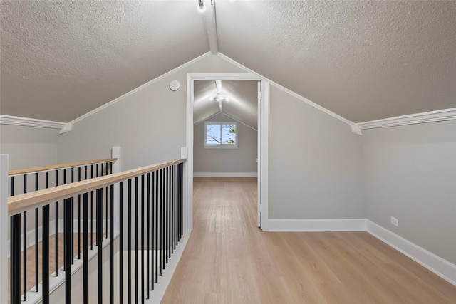 interior space featuring vaulted ceiling, ornamental molding, a textured ceiling, and light hardwood / wood-style flooring