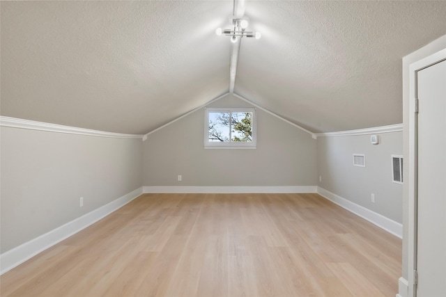 bonus room with a textured ceiling, light wood-type flooring, and vaulted ceiling