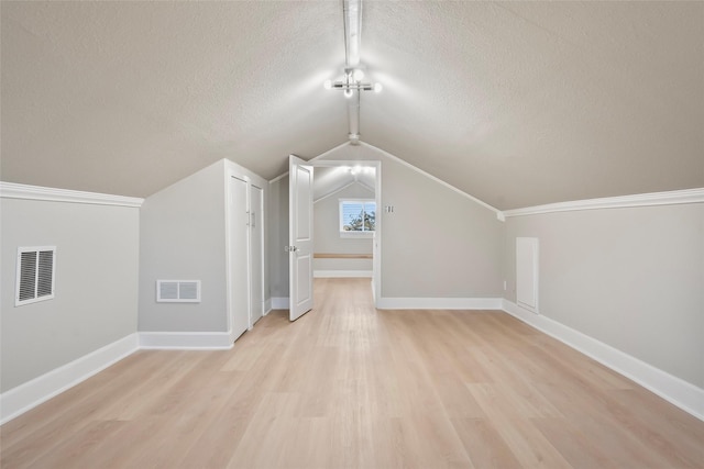 additional living space with a textured ceiling, light wood-type flooring, and lofted ceiling