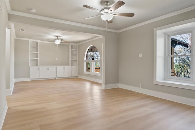 empty room with built in shelves, light hardwood / wood-style floors, ceiling fan, and crown molding