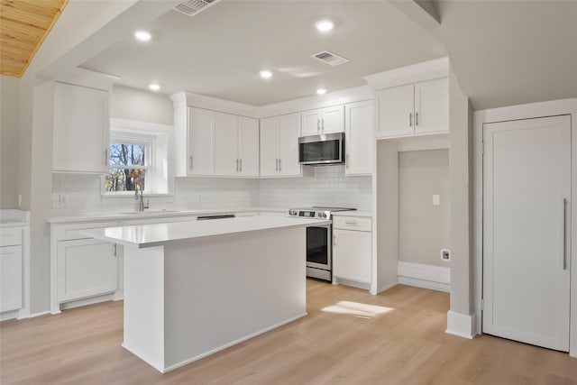 kitchen featuring light hardwood / wood-style floors, a kitchen island, white cabinetry, and stainless steel appliances