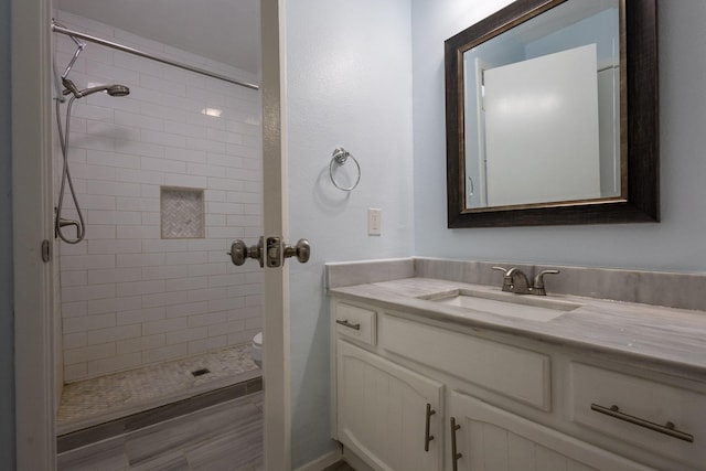 bathroom with a tile shower, vanity, and toilet