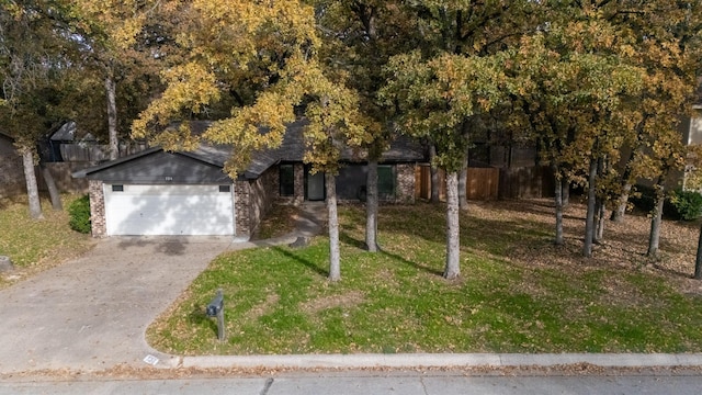 view of property hidden behind natural elements featuring a garage and a front lawn