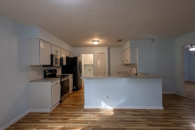 kitchen featuring white cabinetry, decorative backsplash, light hardwood / wood-style floors, kitchen peninsula, and stainless steel appliances