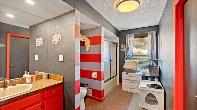 full bathroom with tile patterned flooring, combined bath / shower with glass door, a textured ceiling, toilet, and vanity